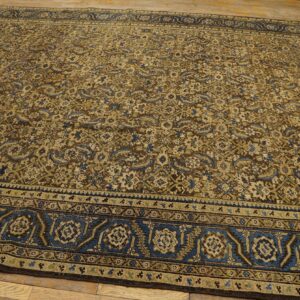Intricate all-over patterned rug in brown, beige, blue, and green on plank wood flooring.