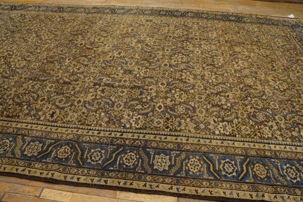 Intricate all-over patterned rug in brown, beige, blue, and green on plank wood flooring.