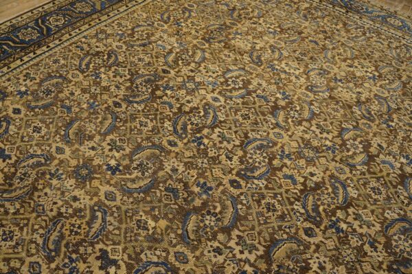 Traditional brown rug with dense blue and tan patterns, featuring a dark border on wood flooring.