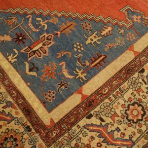 Geometric rug corner featuring a distressed blue field and complex borders in rust red and light tan.