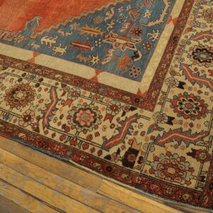 Low-pile rug with geometric patterns in terracotta, dusty blue, and tan on distressed wood planks.