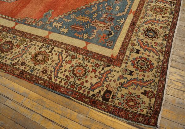 Low-pile rug with geometric patterns in terracotta, dusty blue, and tan on distressed wood planks.