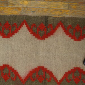 Beige flatweave runner featuring a bold red and dark green geometric border on rustic wood flooring.