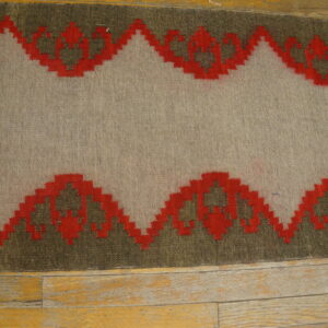 Flatweave runner in beige, red, and olive green with a geometric scalloped pattern on wood floors.