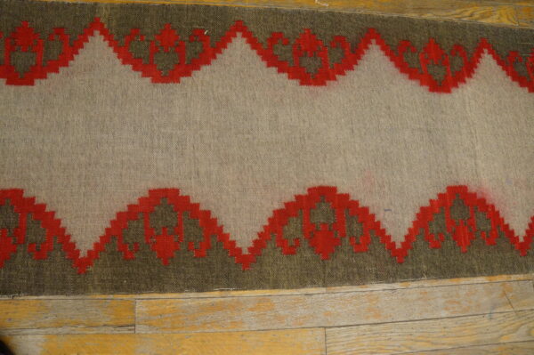 Flatweave runner in beige, red, and olive green with a geometric scalloped pattern on wood floors.
