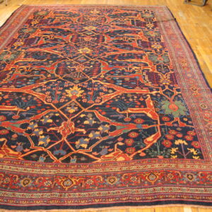 Dark blue rug with stylized red and yellow animal patterns and complex borders rests on a hardwood floor.