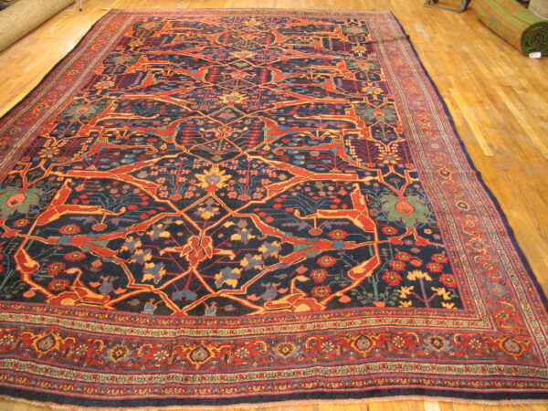 Dark blue rug with stylized red and yellow animal patterns and complex borders rests on a hardwood floor.
