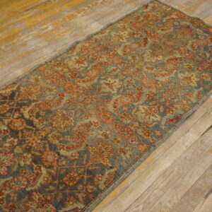 Low-pile blue and terracotta floral runner rug lying on distressed, light wooden floorboards.