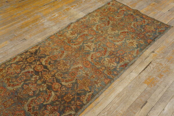 Low-pile blue and terracotta floral runner rug lying on distressed, light wooden floorboards.