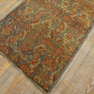 Muted blue and rust patterned rug with low pile lying on distressed light-colored wood planks.