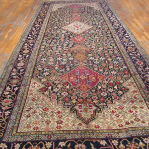 Ornate runner rug featuring a navy blue field, red medallions, and cream accents on wood flooring.