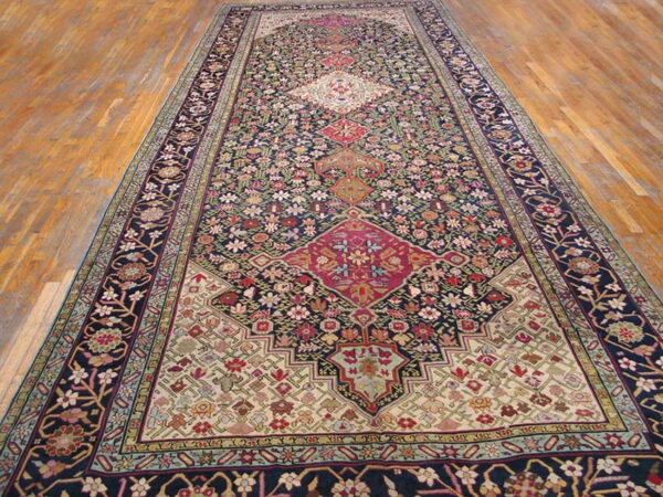 Ornate runner rug featuring a navy blue field, red medallions, and cream accents on wood flooring.