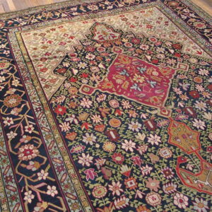 Ornate navy blue rug with a dense red, cream, and multicolor floral pattern rests on wood planks.