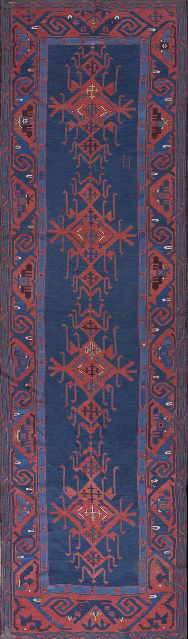 Deep indigo runner rug with repeating rust red geometric tribal designs and thick patterned borders.
