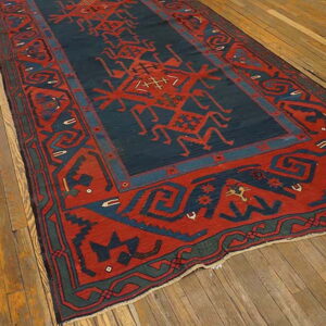 A long rug featuring red and navy geometric tribal patterns lies on a wide-plank wooden floor.