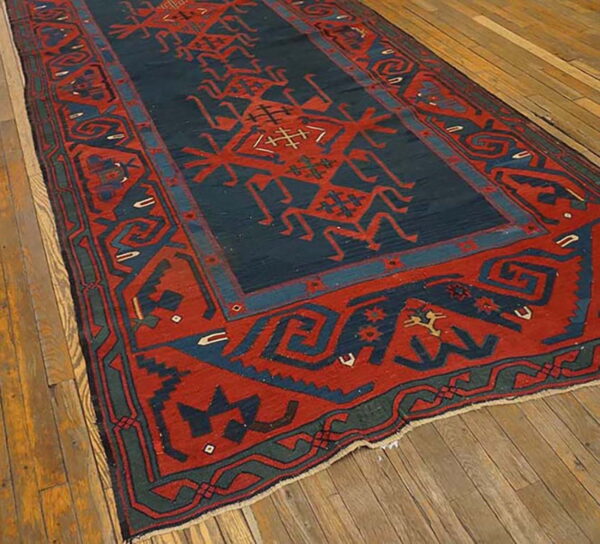 A long rug featuring red and navy geometric tribal patterns lies on a wide-plank wooden floor.