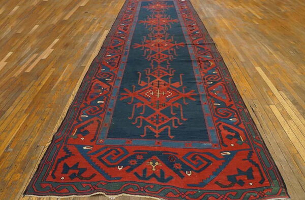 Long runner rug in dark blue and red geometric tribal patterns rests on a light brown wood floor.