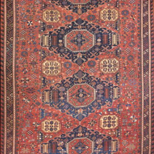 Intricate traditional rug featuring navy blue geometric medallions on a dense brick red field.