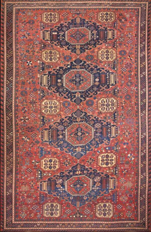 Intricate traditional rug featuring navy blue geometric medallions on a dense brick red field.