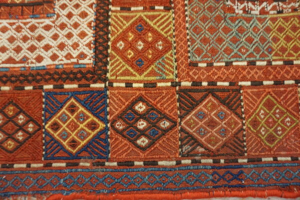 Geometric flatweave detail showing complex diamonds and lattice patterns in rust, blue, yellow, and cream.