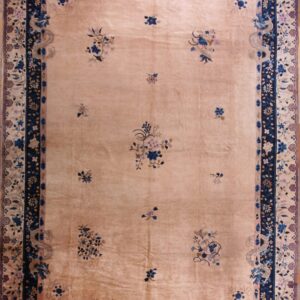 Low pile beige rug with sparse blue and mauve floral sprays and a detailed navy border featuring dragons.