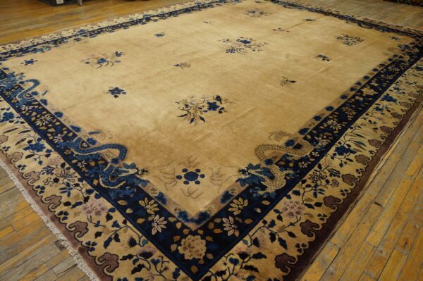 Large tan rug with dark blue borders featuring scattered floral motifs and prominent stylized dragons on wood flooring.
