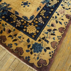 Ornate floral rug in gold, deep blue, and mauve borders lies on light wooden floors.
