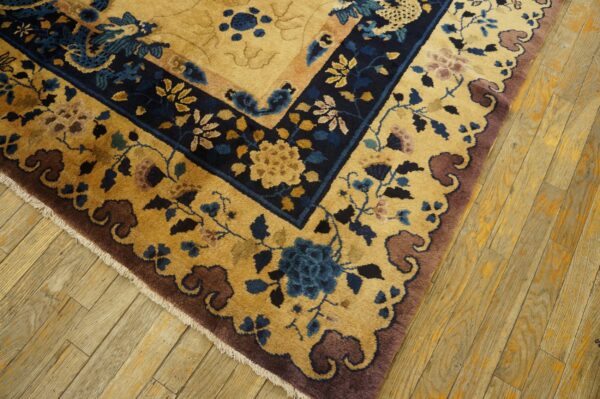 Ornate floral rug in gold, deep blue, and mauve borders lies on light wooden floors.
