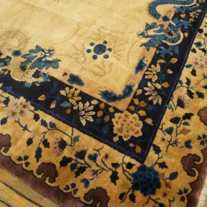 High-pile tan and navy rug with intricate floral and dragon patterns on distressed hardwood floors.