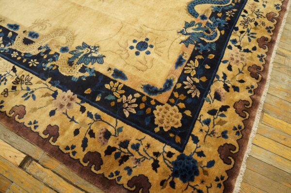 High-pile tan and navy rug with intricate floral and dragon patterns on distressed hardwood floors.