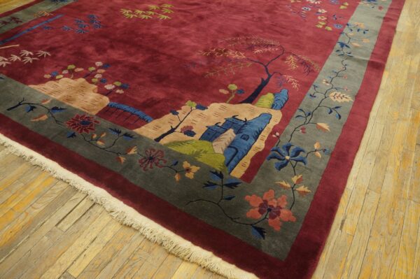Burgundy rug featuring a pictorial landscape pattern and a wide gray floral border rests on wood flooring.