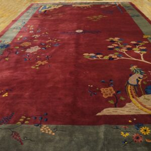 A large maroon rug with a figural bird and detailed floral border rests on light wood floors.
