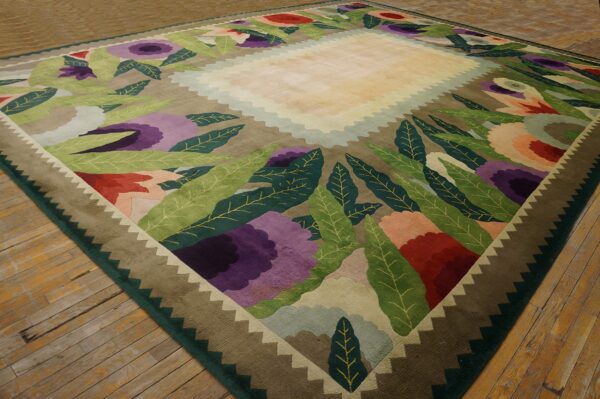 Olive and purple floral rug with stylized leaves and a zigzag border on distressed wood floors.