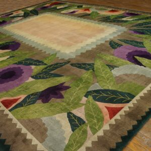 Square rug featuring a bold floral and leaf design in green, purple, and red on brown wood floors.