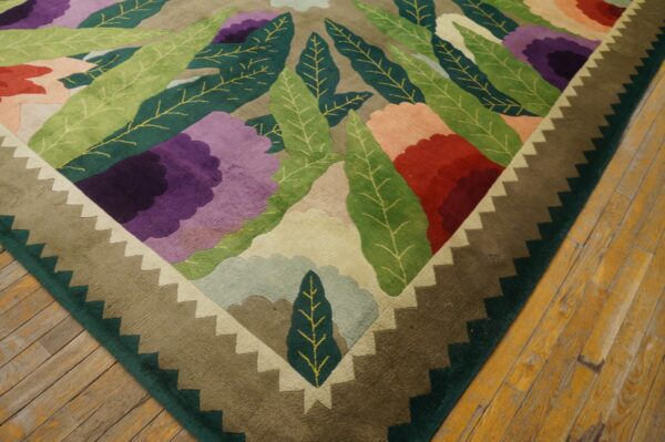 A multicolored floral rug with a carved pile and stepped border rests on distressed wood plank flooring.