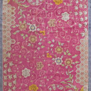 Magenta rug with yellow, white, and pale green scrolling floral motifs and hexagonal border elements.