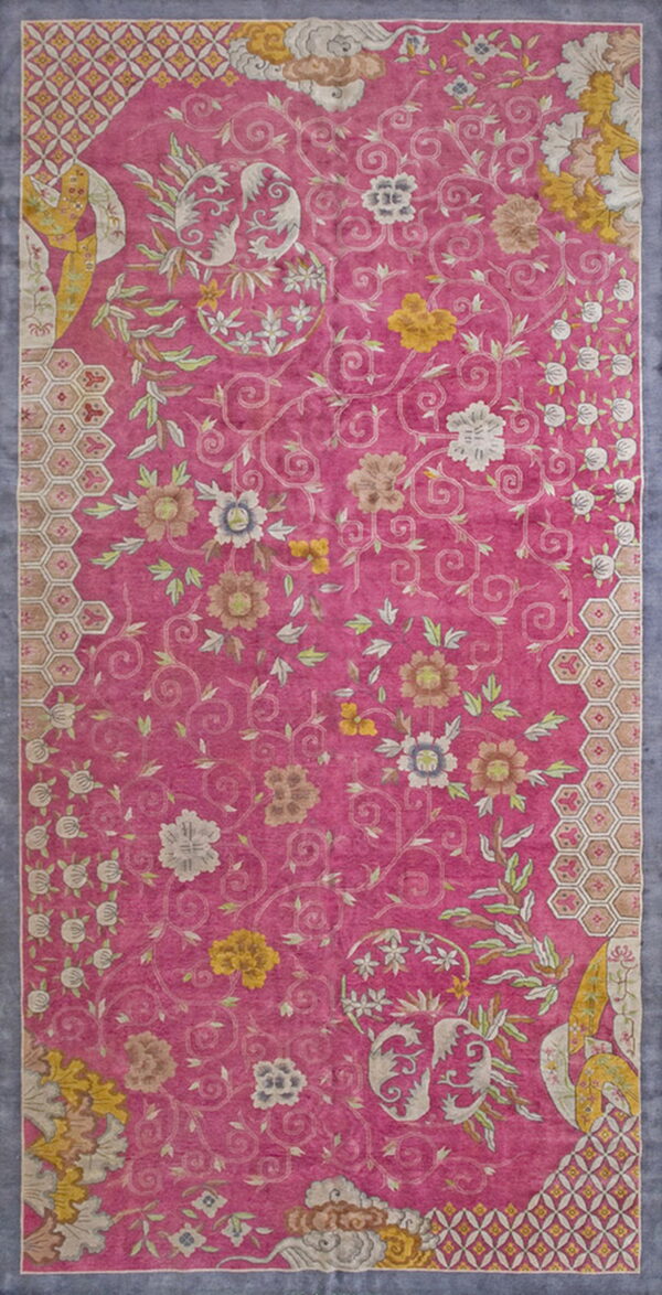 Magenta rug with yellow, white, and pale green scrolling floral motifs and hexagonal border elements.