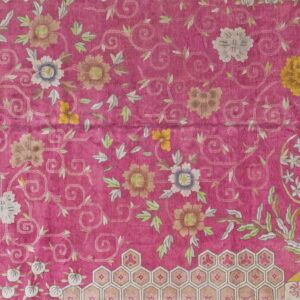 Detail of a vivid magenta rug patterned with scrolling foliage, pale flowers, and honeycomb borders.