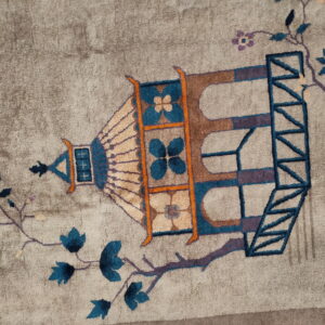 Low-pile greige rug with an ornate teal, brown, and purple lantern design and stylized floral branches.