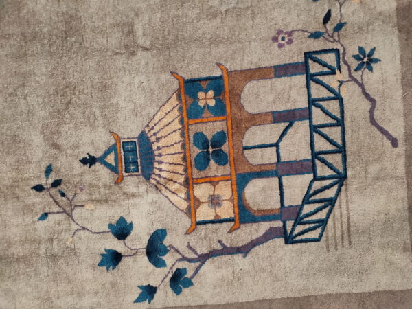 Low-pile greige rug with an ornate teal, brown, and purple lantern design and stylized floral branches.