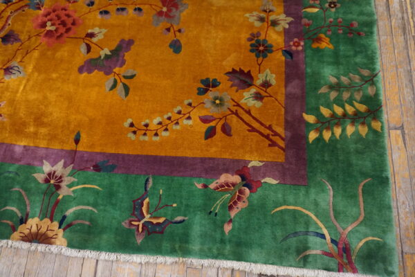 Plush gold rug with a green border and multicolored floral and butterfly patterns on hardwood floors.