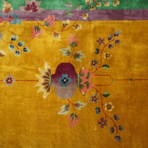 Golden yellow plush rug featuring a central vase and winding multicolored floral motifs and borders.