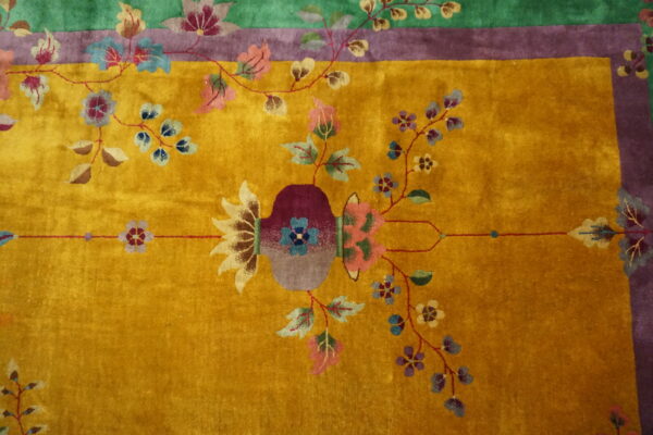 Golden yellow plush rug featuring a central vase and winding multicolored floral motifs and borders.