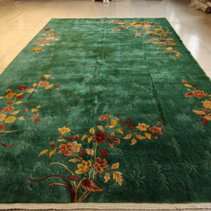 A large green carved rug featuring scattered multicolored floral sprays on light-colored tiled flooring.