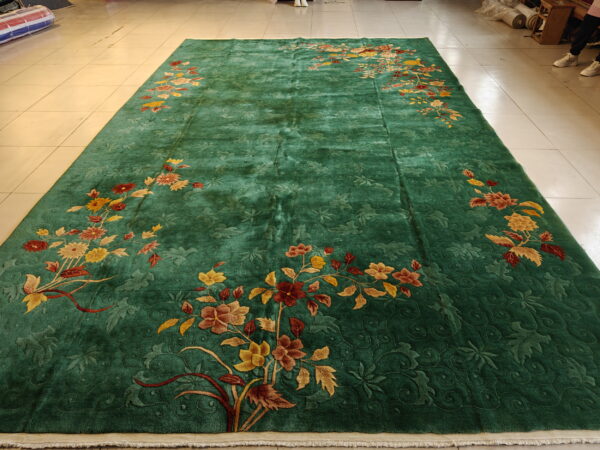 A large green carved rug featuring scattered multicolored floral sprays on light-colored tiled flooring.