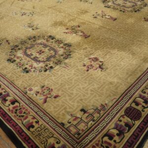 Beige rug featuring a subtle geometric field, multicolored floral accents, and layered borders on wood plank flooring.