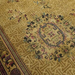 Gold low-pile rug with a geometric lattice field, colorful floral motifs, and a complex stepped border.