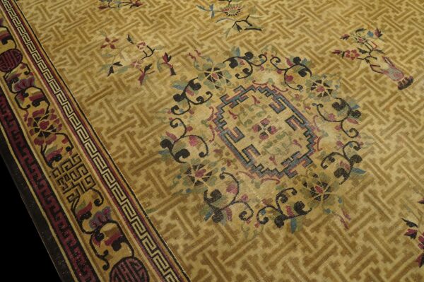 Gold low-pile rug with a geometric lattice field, colorful floral motifs, and a complex stepped border.