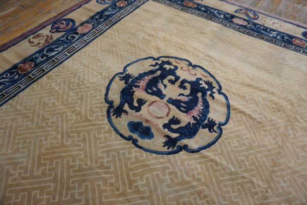 Tan rug with a maze pattern, blue dragon medallion, and complex floral borders on wooden floorboards.