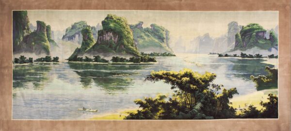 Panoramic green and blue landscape rug showing towering mountains, water, and bamboo, with a wide brown border.